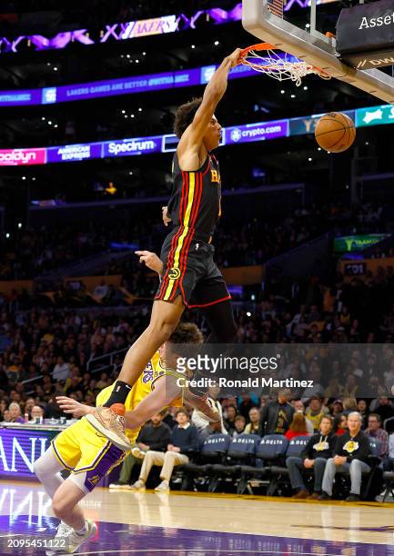 Jalen Johnson of the Atlanta Hawks makes the slam dunk and fouled by Austin Reaves of the Los Angeles Lakers in the first half at Crypto.com Arena on...