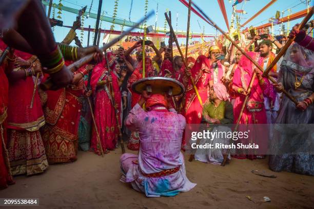 Women hit revellers with sticks during "Lathmar Holi" as part of the Hindu spring festival Holi at the Radharani temple on March 18, 2024 in Barsana,...