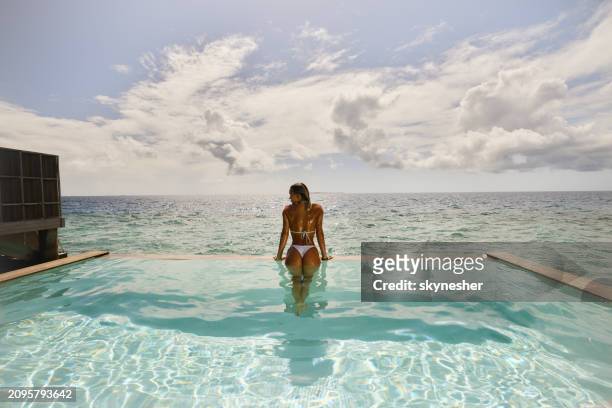 rear view of carefree woman spending a summer day in swimming pool by the sea. - meeru island stockfoto's en -beelden