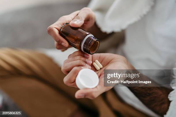 close up of palm with pills from pill bottle. man is sick, taking medication, painkillers, man with cold. - dose foto e immagini stock