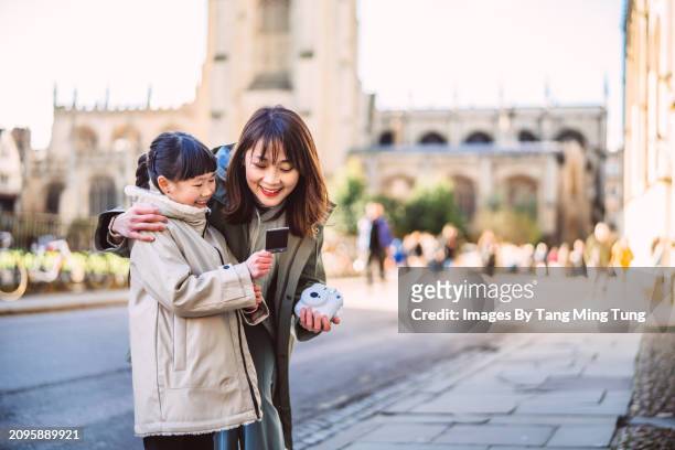 mom & young daughter reviewing instant photos after taking pictures from instant camera while exploring in tourist district of an old town during vacation - afterr stock pictures, royalty-free photos & images
