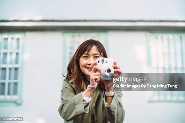 beautiful asian female traveller taking pictures with an instant camera in tourist district of a town - photographic equipment stock pictures, royalty-free photos & images