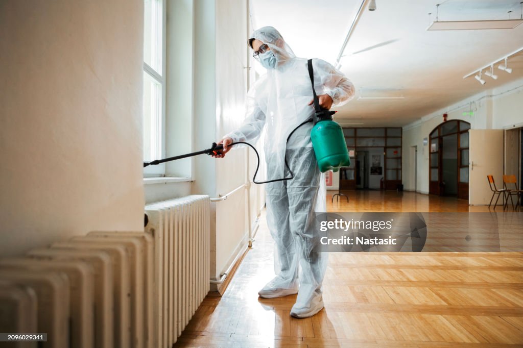Exterminator Applying Pesticide with Sprayer