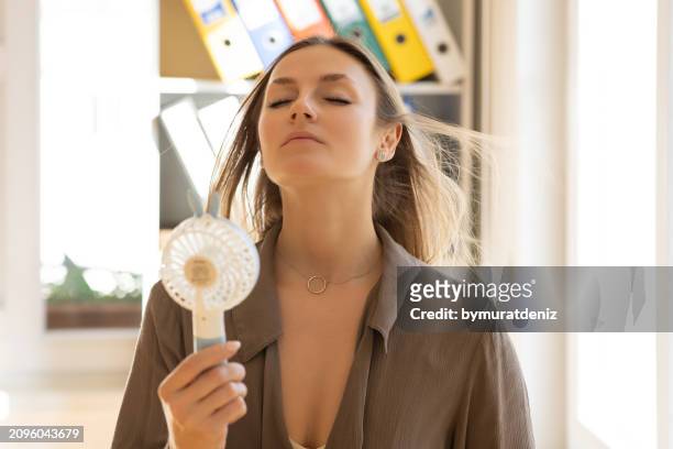woman with fan giving her air and a fan in her hand - ac weary stockfoto's en -beelden