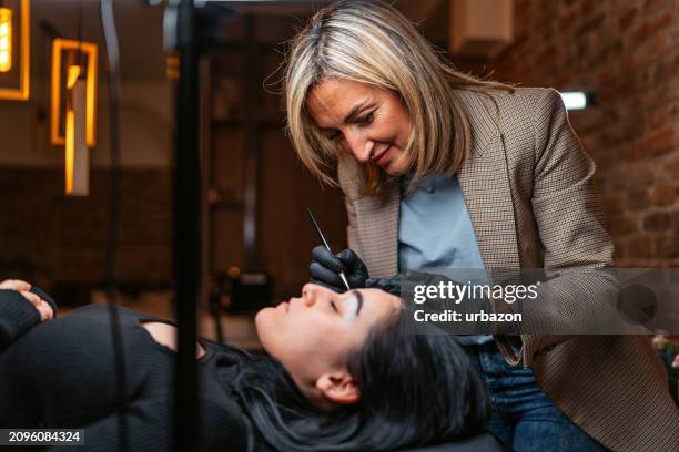 female beautician microblading her client's eyebrows at a beauty salon - female body waxing stock pictures, royalty-free photos & images