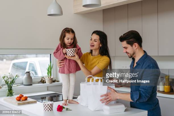 girl standing on kitchen countertop, island, picking ordered food, takeout lunch, out of bag. - man eating at diner counter foto e immagini stock