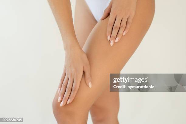 woman applying body cream - leg stock pictures, royalty-free photos & images