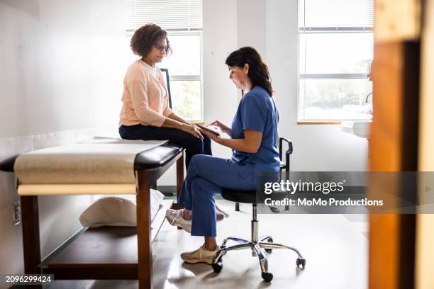 doctor and senior woman discussing treatment in doctors office - doctor stethoscope patient whole body stock pictures, royalty-free photos & images
