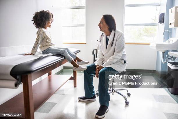doctor and young girl talking in exam room - doctor stethoscope patient whole body stock pictures, royalty-free photos & images
