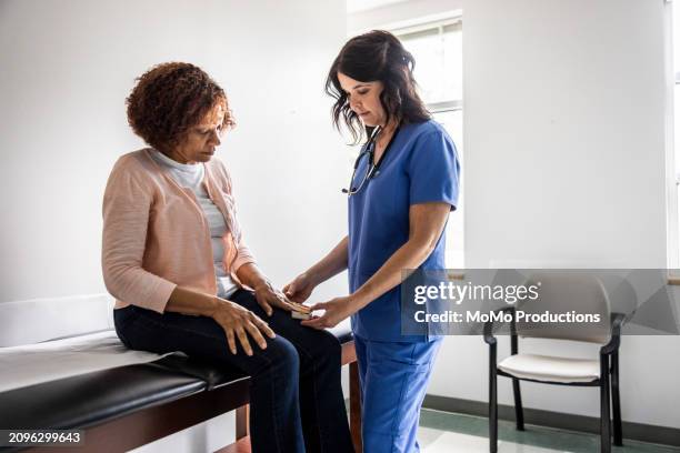 nurse checking senior woman's blood oxygen in exam room - artrite foto e immagini stock