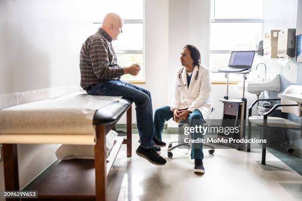doctor and senior man discussing treatment in exam room - doctor stethoscope patient whole body stock pictures, royalty-free photos & images