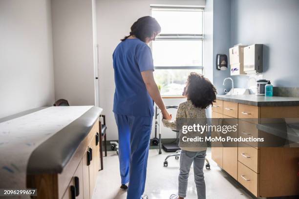 nurse leading young girl into exam room - pediatric nurse stock pictures, royalty-free photos & images