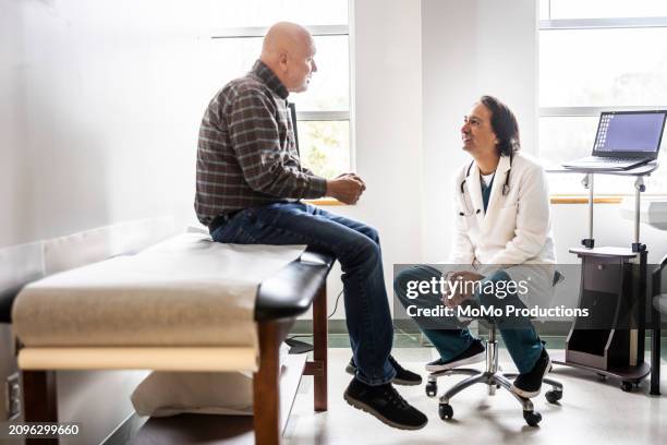doctor and senior man discussing treatment in exam room - doctor stethoscope patient whole body stock pictures, royalty-free photos & images