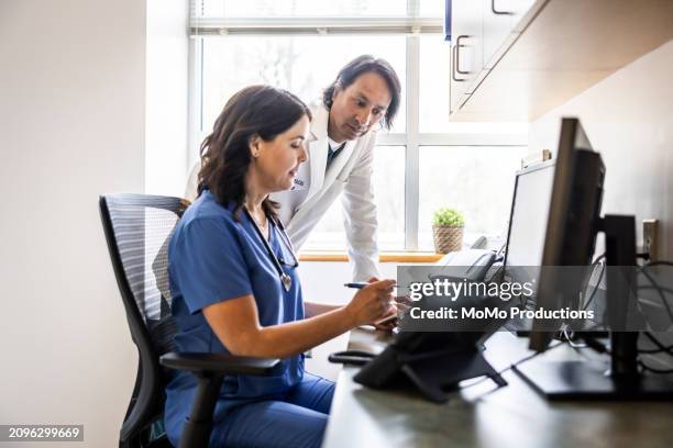 doctor and nurse reviewing records in medical office - emr data stock-fotos und bilder