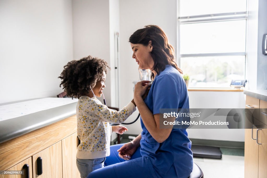 Young girl listening to nurses heart with stethoscope