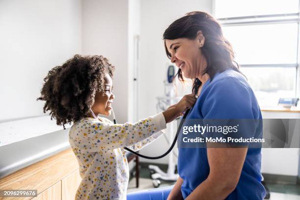 young girl listening to nurses heart with stethoscope - pédiatre photos et images de collection