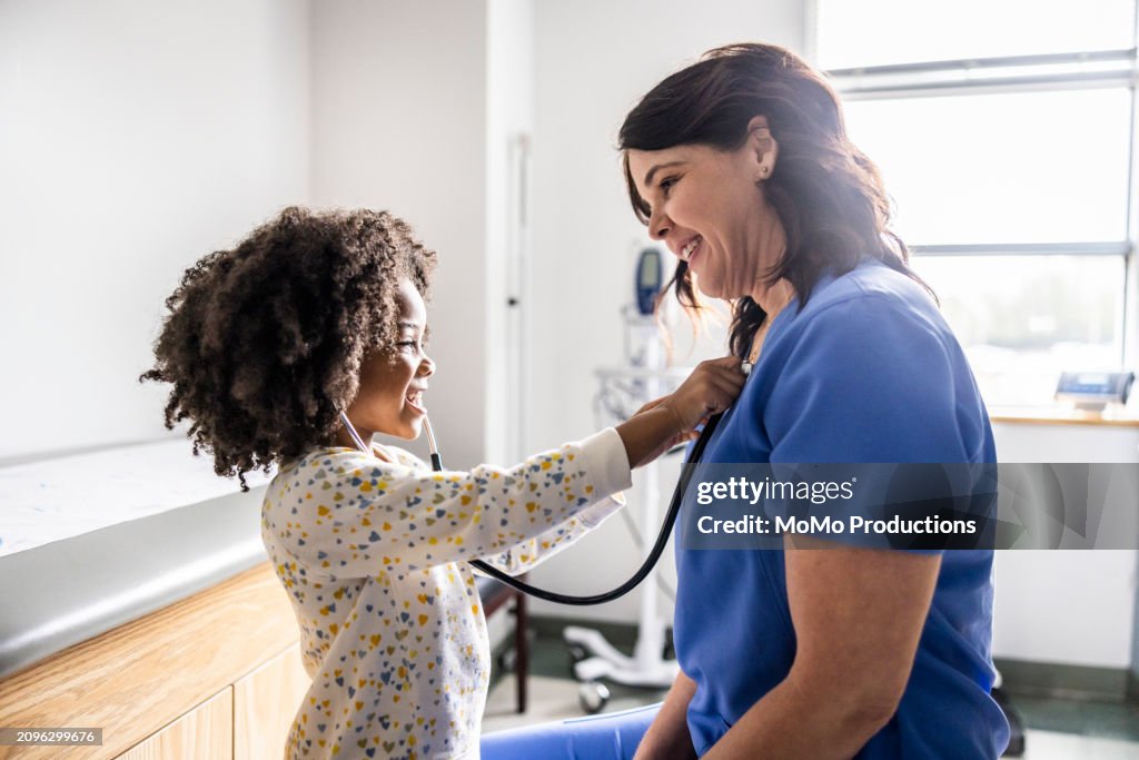 Young girl listening to nurses heart with stethoscope
