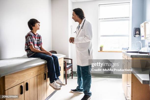 doctor and young boy talking in exam room - doctor stethoscope patient whole body stock pictures, royalty-free photos & images