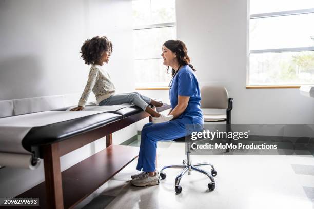 nurse and young girl talking in exam room - doctor stethoscope patient whole body stock pictures, royalty-free photos & images