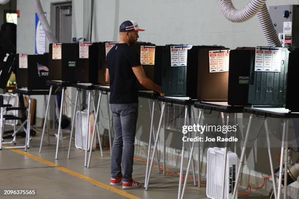 Poll worker prepares a voting booth as he waits for voters to arrive at the Miami Beach Fire Station 4 to cast their ballot during the primary on...