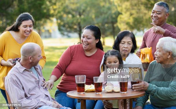 multi-generation multiracial family eating in back yard - filipino family reunion stock pictures, royalty-free photos & images