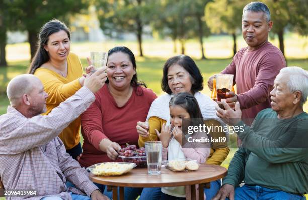 multi-generation multiracial family eating in back yard - filipino family reunion stock pictures, royalty-free photos & images