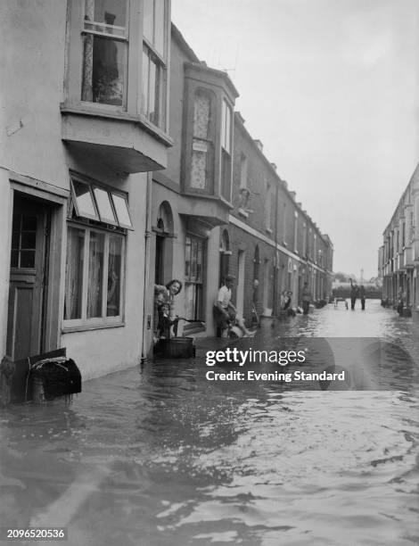 Weymouth residents looking out of their homes in a flooded street, Dorset, July 19th 1955.