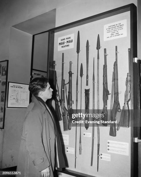 Mr SB Lucas looks at a display of 'Hand Made Mau-Mau Weapons' inside a cabinet at the Imperial War Museum, London, December 15th 1955.