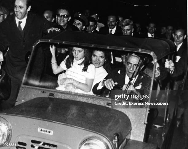 Jaqueline Kennedy Onassis sits with her daughter, Caroline Kennedy, on her lap while driving away from the chapel with her new husband, Greek...