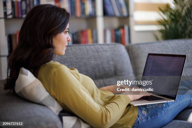 smiling young woman using laptop at home - form filling stock pictures, royalty-free photos & images