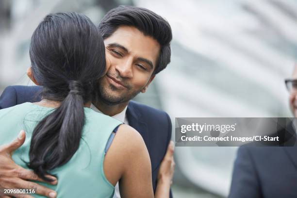 businesspeople greeting each other with kiss on cheek - guancia foto e immagini stock