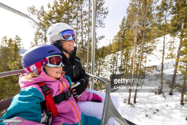 a grandmother and her granddaughter riding a chairlift while skiing together. - light vivid children senior young focus stock pictures, royalty-free photos & images