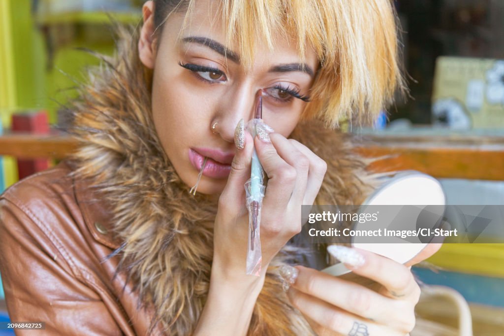 Young woman applying eyeliner