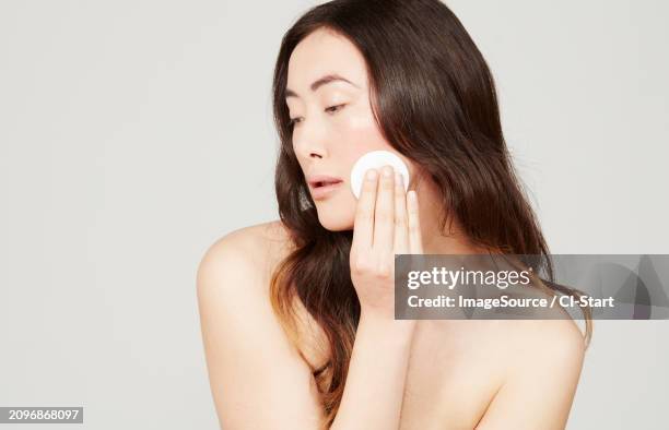 young woman wiping face with cotton pad - shoulder pad 個照片及圖片檔