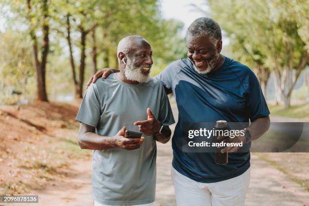 due amici anziani neri che camminano insieme nel parco pubblico - solo uomini foto e immagini stock