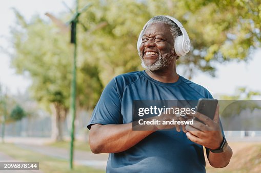 Senior man using smartphone while running in public park Senior man using smartphone while running in public park