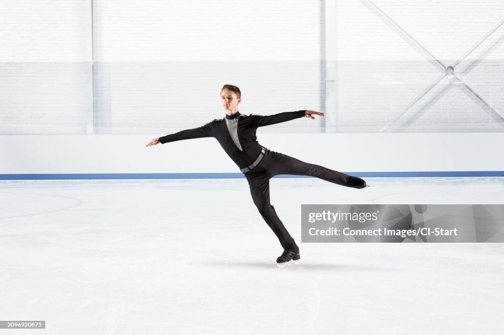 Young man figure skating on ice rink