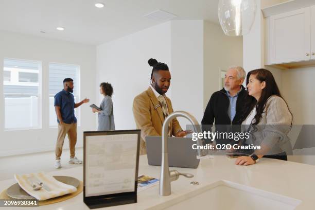 real estate agent showing a new home to prospective buyers - visita de inmuebles en venta fotografías e imágenes de stock