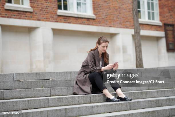 woman holding smart phone on staircase - slipper stock-fotos und bilder
