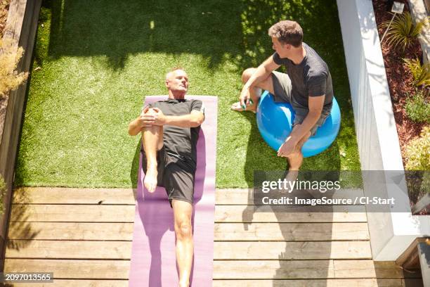 mature couple practicing yoga in back yard - gray shorts stock pictures, royalty-free photos & images