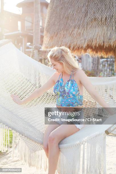 young woman wearing patterned crop top on hammock - hot blondes images stock pictures, royalty-free photos & images