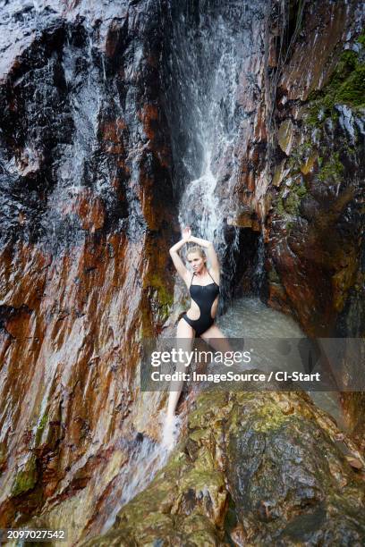 young woman wearing black swimsuit by waterfall - hot blondes images stock pictures, royalty-free photos & images