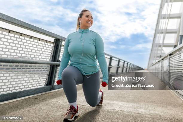 overweight woman exercising with dumbbells - obesitas stockfoto's en -beelden