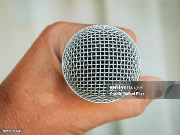 human hand grabbing microphone - cantor escritor de canções imagens e fotografias de stock