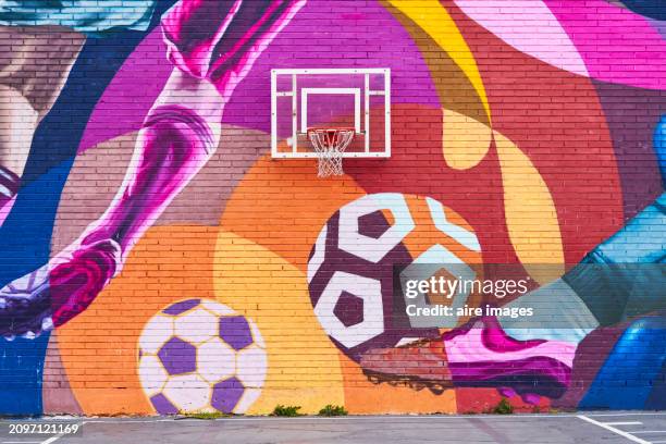front view of a basketball backboard on a wall with painted sports mural in the foreground - murale foto e immagini stock