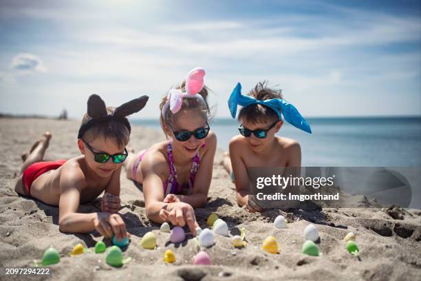 kids playing on the beach with easter eggs - easter egg hunt stock pictures, royalty-free photos & images