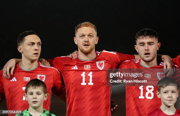 Danny Gosset, Sion Bradley and Josh Williams of Wales C sing their national anthem prior to the International Challenge Match between Wales C and...