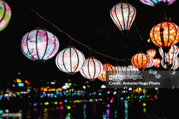 colorful lanterns hanging in hoi an. with the city and the river in the background - hanoi cityscape stock pictures, royalty-free photos & images