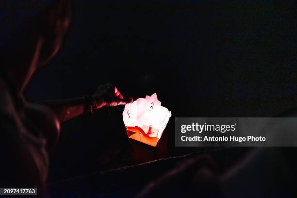 woman releasing a lighted candle into the river in hoi an - hanoi cityscape stock pictures, royalty-free photos & images