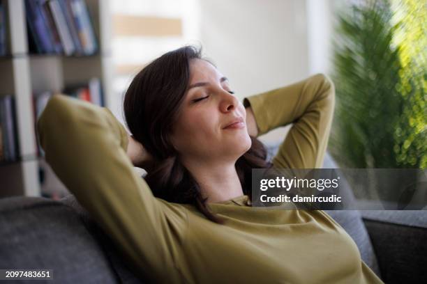 happy smiling woman relaxing on sofa at home - facilidade imagens e fotografias de stock